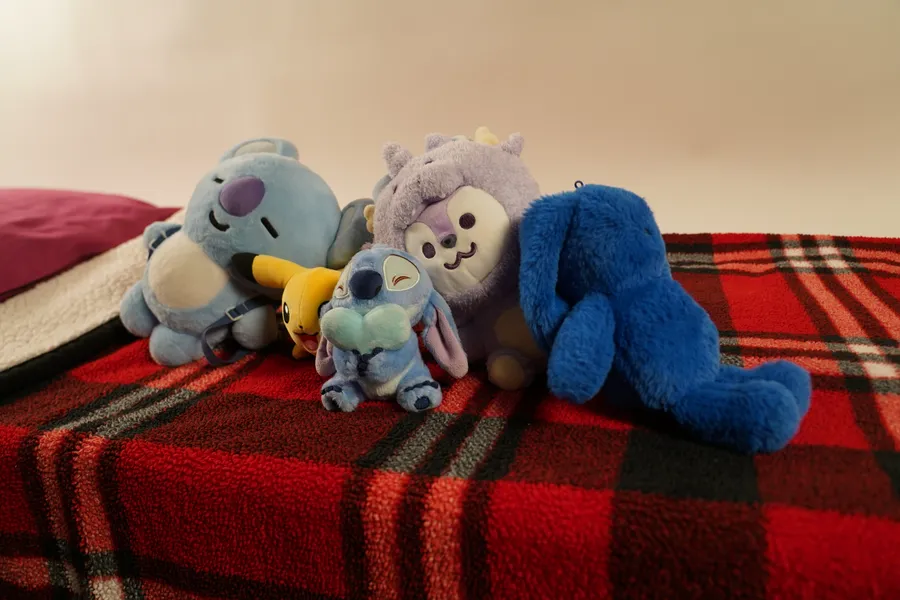 Several plush dolls sitting together on a bed