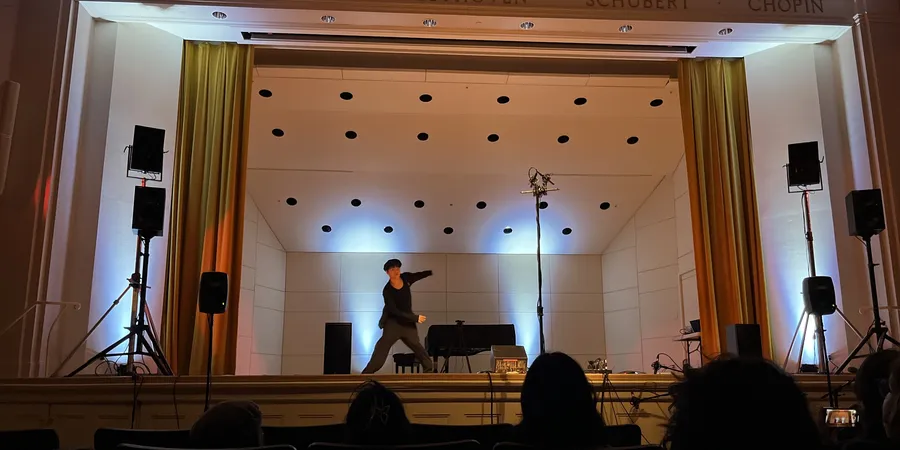 Zhixing Chen dancing the opening solo of unscored on the Paine Hall stage, audience in the foreground